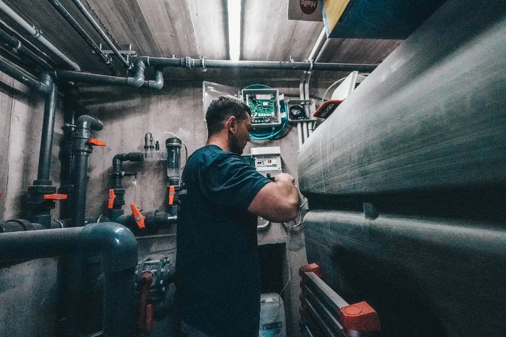 Técnico revisando los equipos de una sala de máquinas de piscina